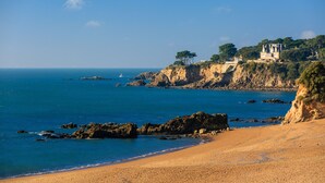 A coastal landscape with a sandy beach, rocky outcrops, and a cliff with a building. - Best Western Hotel De La Plage (Saint-Nazaire)