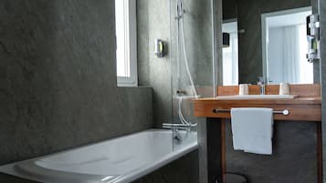 Un baño moderno con bañera, tocador de madera, espejo y perchero.