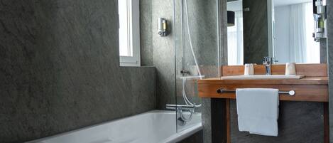 A modern bathroom with a bathtub, a wooden vanity, a mirror, and a towel rack.