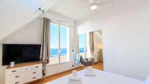 A bedroom with a TV, a bed with towels, a chair, and a view of the beach. - Best Western Hotel De La Plage (Saint-Nazaire)