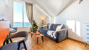 A modern living room with a sofa, a coffee table, and a dining area with chairs. - Best Western Hotel De La Plage (Saint-Nazaire)