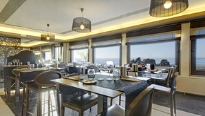 A modern dining area with large windows, a bar, and a view of the sea. - Best Western Hotel De La Plage (Saint-Nazaire)