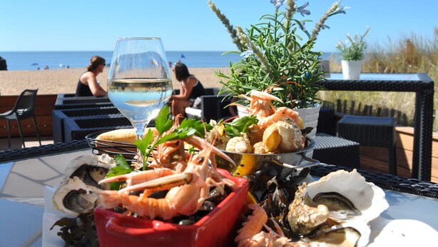 A table with seafood and a glass of water, an umbrella, and a view of the beach. - Best Western Hotel De La Plage (Saint-Nazaire)