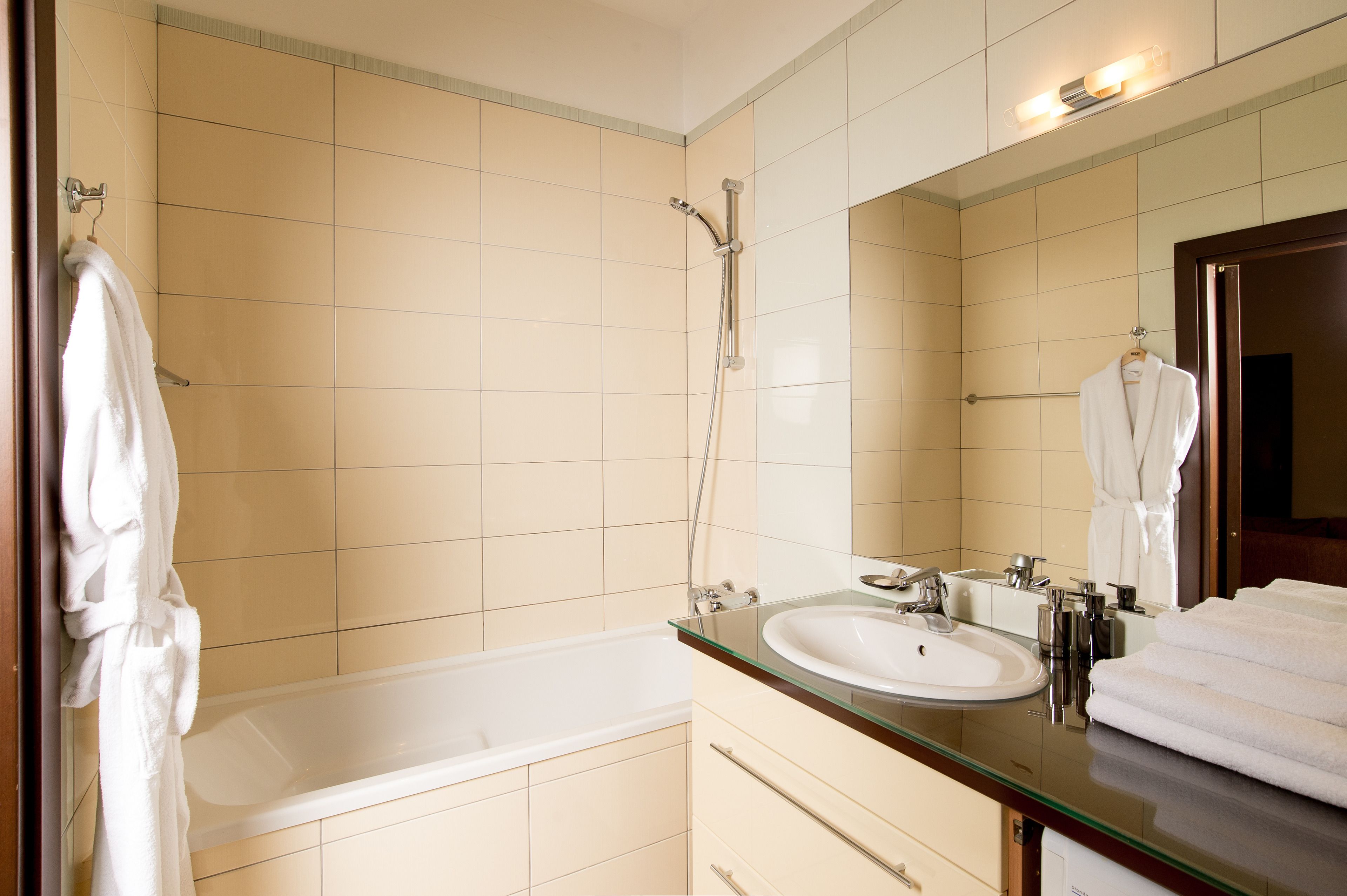 A modern bathroom with a glass-enclosed bathtub, a large mirror, and a white sink.