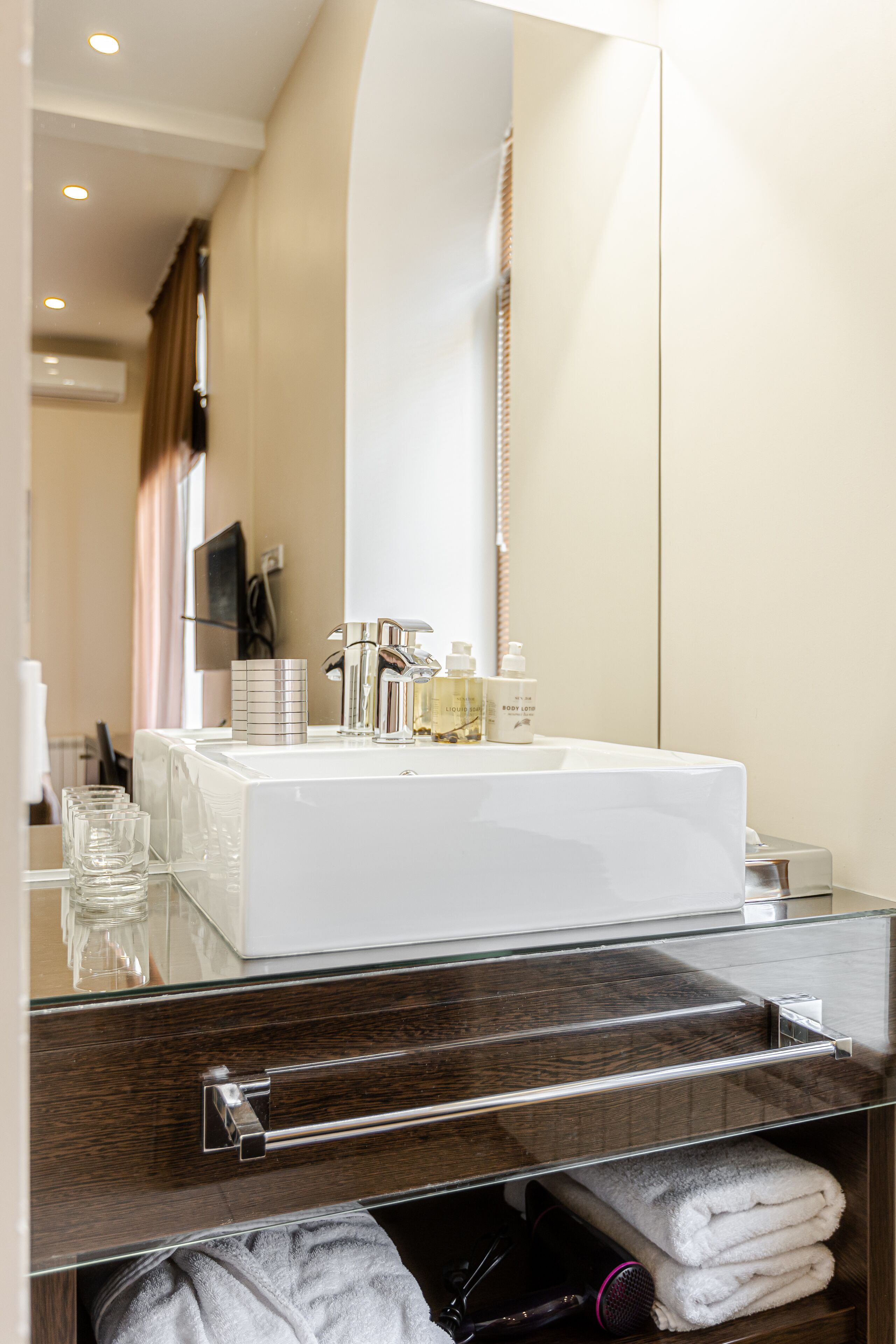 A modern bathroom with a large mirror, a white sink, and a glass shower enclosure.