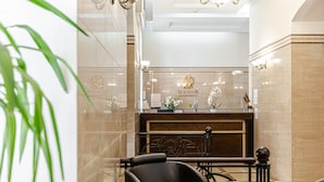 A hotel reception area with a marble reception desk, a glass partition, and a seating area with chairs and tables. - Senator City Center (Kyiv)