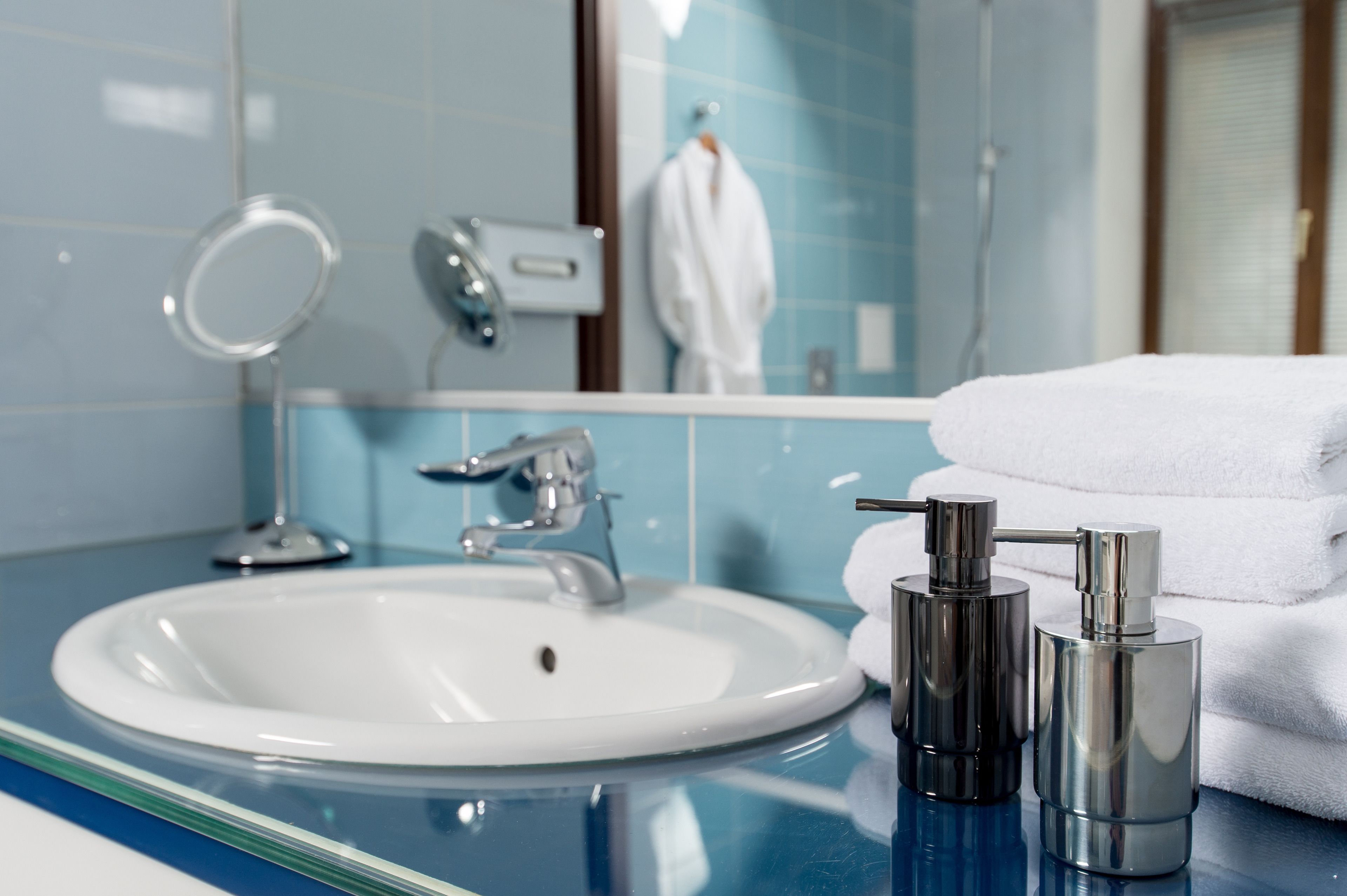 Un baño con un lavabo blanco, un espejo y un perchero para toallas.