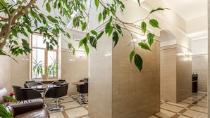 A modern lobby with a checkered floor, a seating area with leather sofas, a dining table, and a large potted plant. - Senator City Center (Kyiv)
