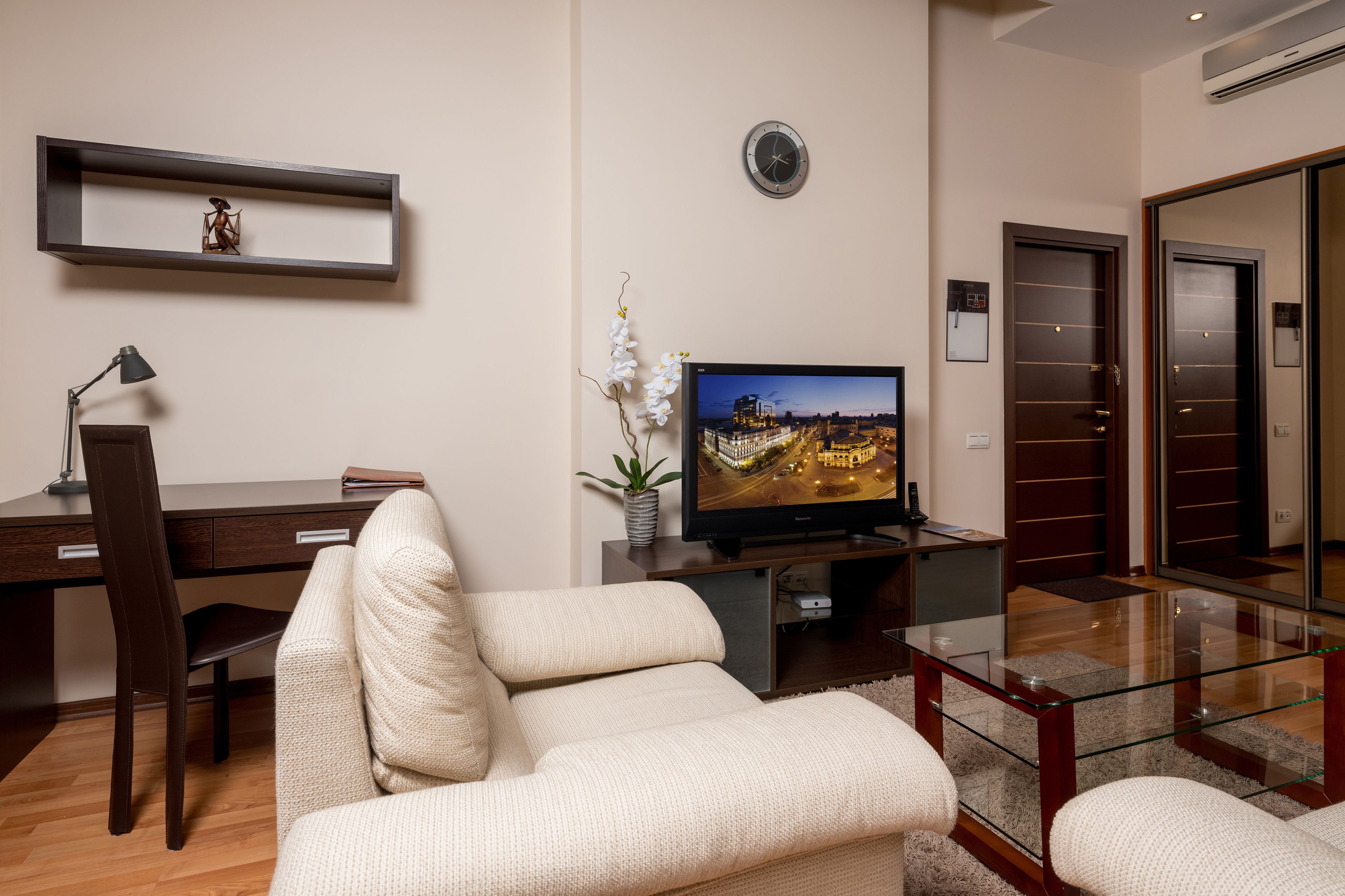 Una sala de estar moderna con un sofá, un televisor, un escritorio y una estantería.