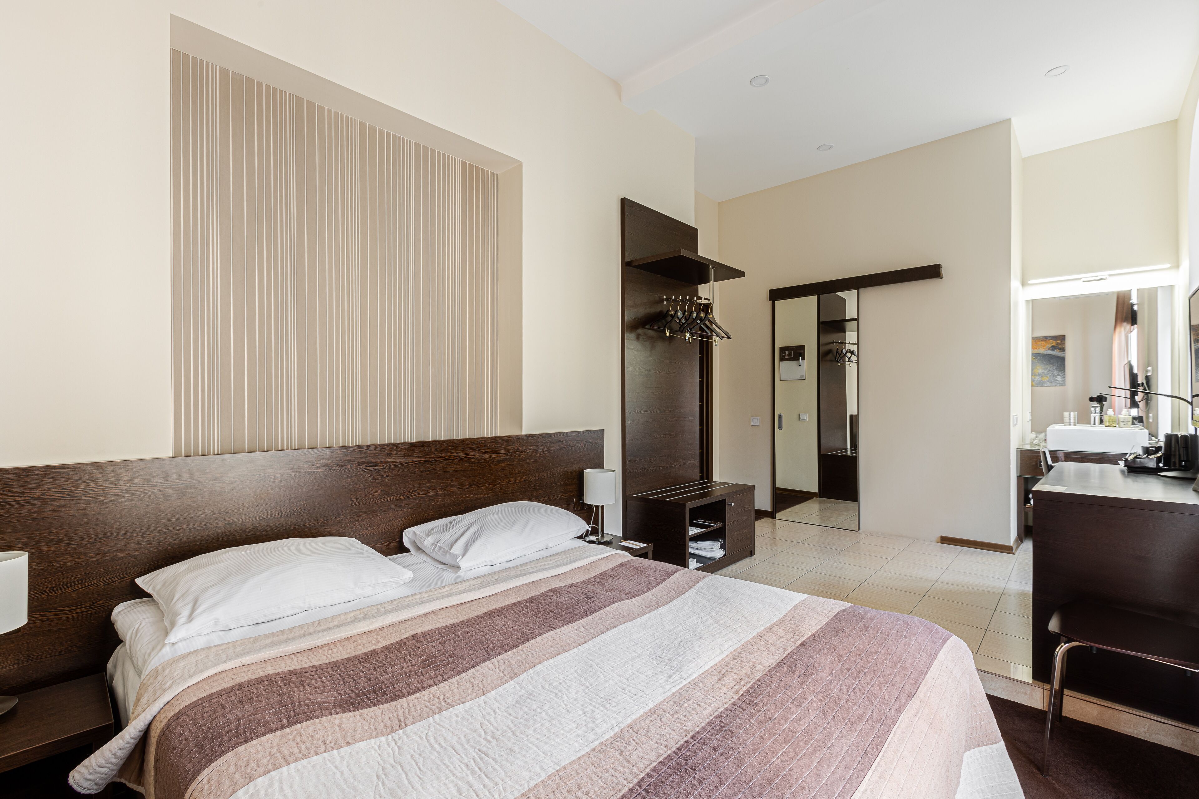 Una habitación de hotel con una cama grande, un escritorio y un espejo.
