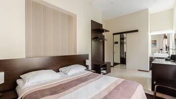 Una habitación de hotel con una cama grande, un escritorio y un espejo.