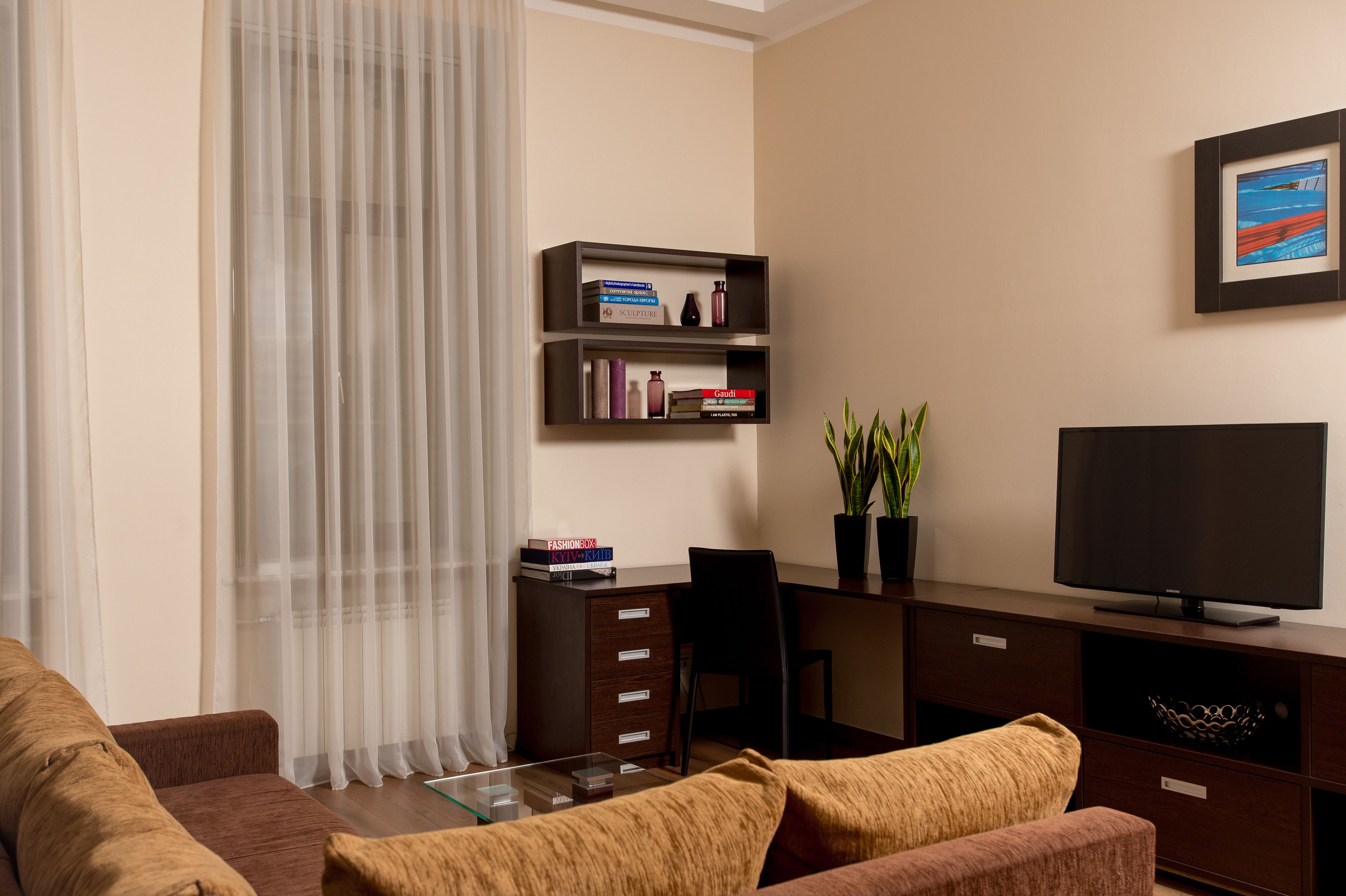 Una sala de estar moderna con un sofá, una mesa de centro, un televisor, una estantería y un escritorio.
