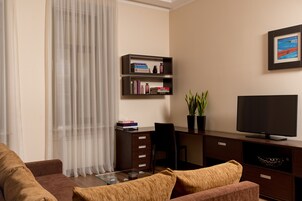 Una sala de estar moderna con un sof á, una mesa de centro, un televisor, una estantería y un escritorio.