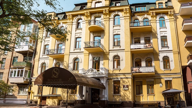A multi-story building with balconies, a sign for 'Senator Apartments', and a covered entrance. - Senator City Center (Kyiv)