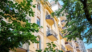 A multi-story building with balconies, large windows, and a tree in the foreground. - Senator City Center (Kyiv)