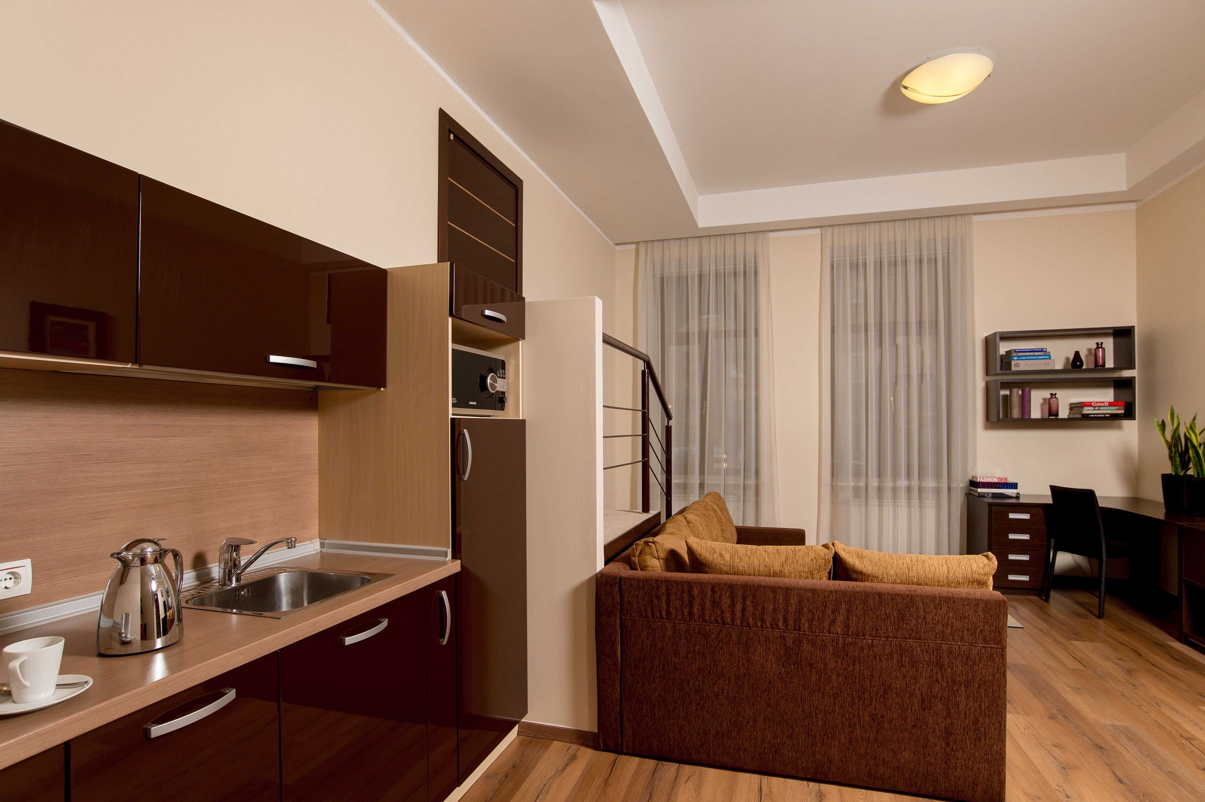 A compact living space with a kitchenette, a sofa, a dining area, and a bookshelf.