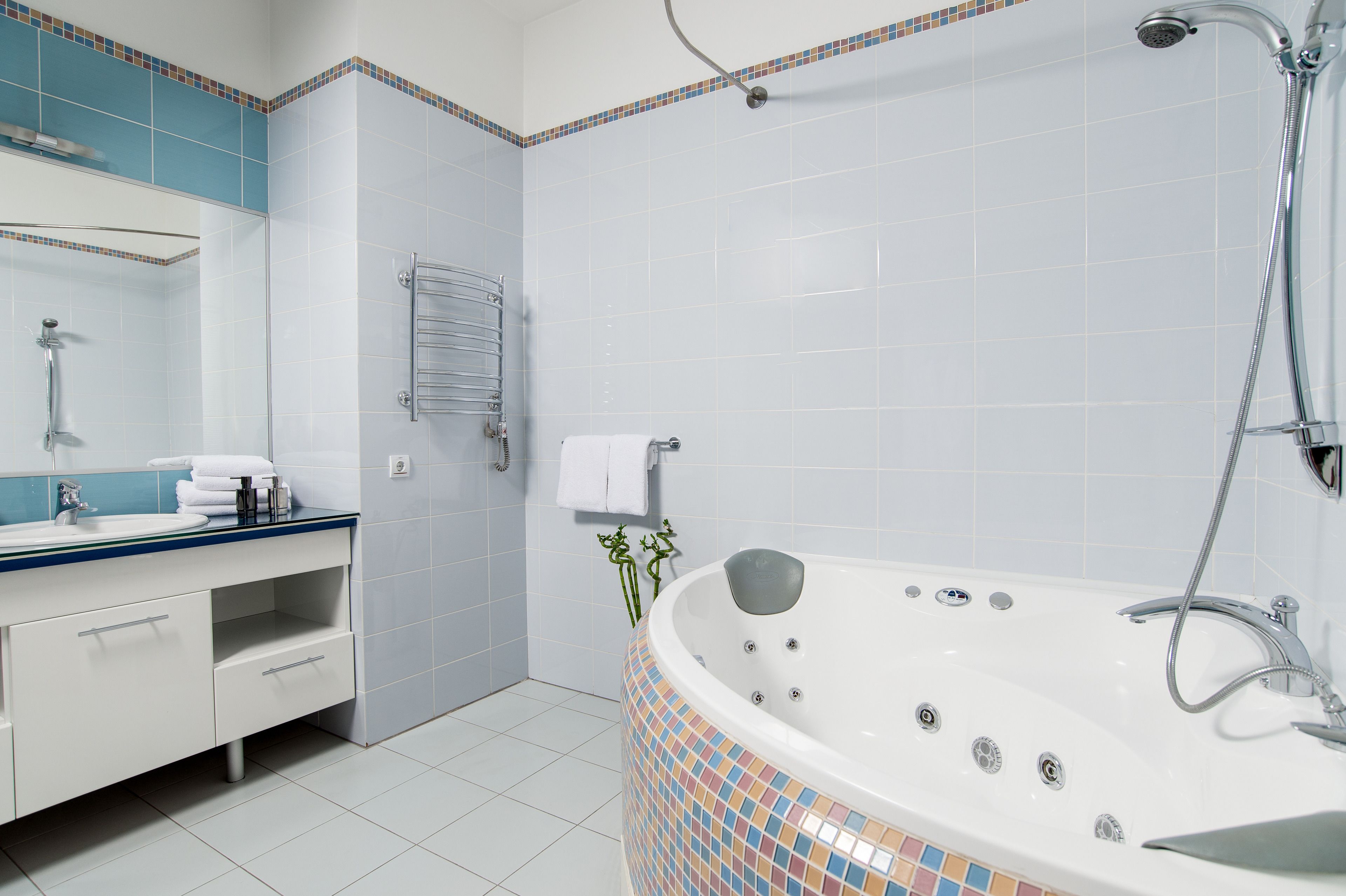 A modern bathroom with a large bathtub, a separate shower area, and a vanity with a mirror.