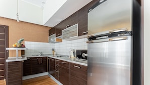 A modern kitchen with dark wood cabinets, stainless steel appliances, and a wooden floor. - Senator City Center (Kyiv)