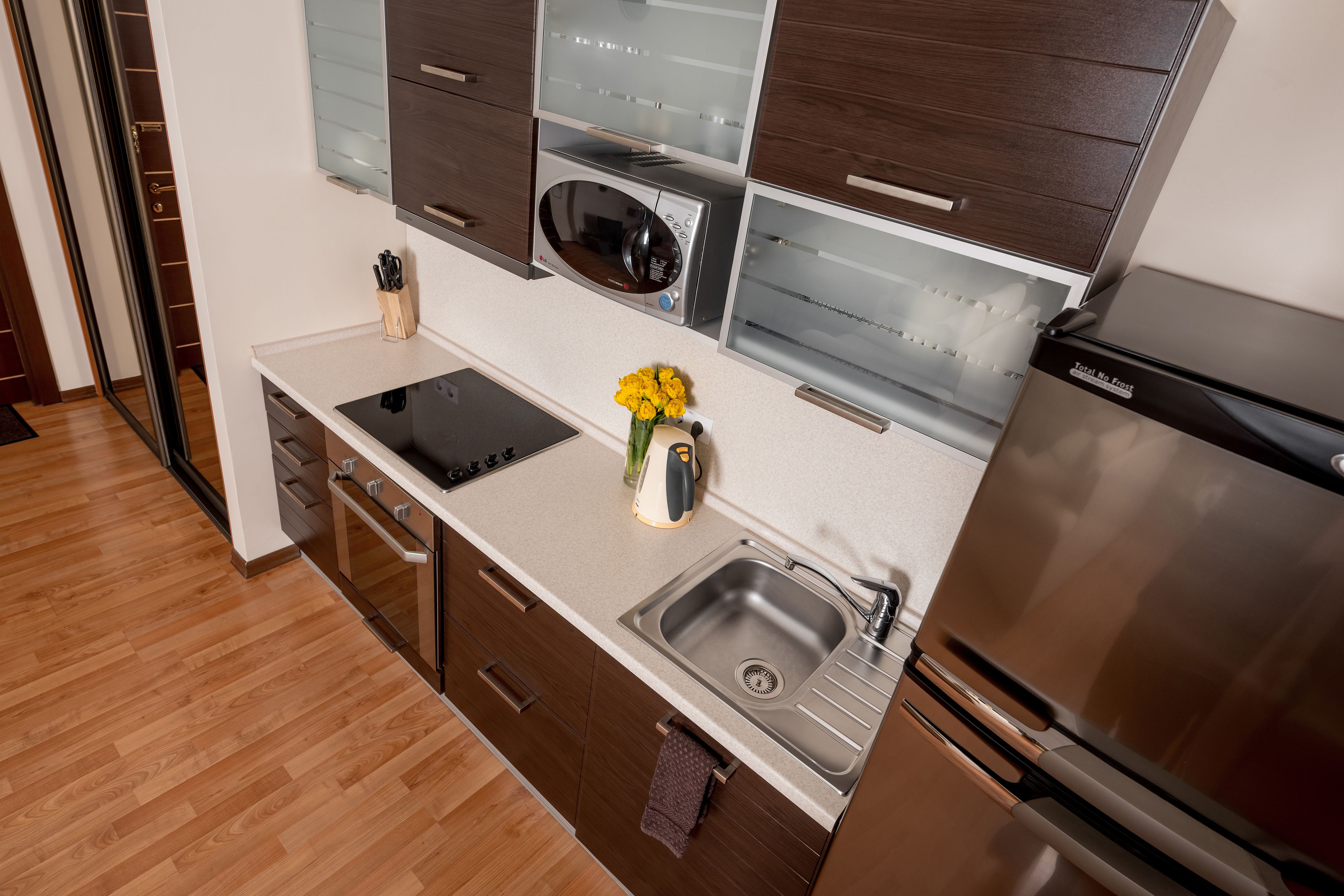 A modern kitchen with a stainless steel sink, a microwave, and a built-in oven.