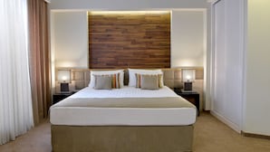 Een hotelkamer met een groot bed, twee nachtkastjes, een houten hoofdbord en een raam met gordijnen.