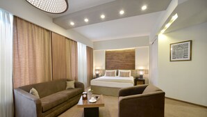 Een hotelkamer met een groot bed, een bank, een stoel en een salontafel.