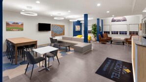 A hotel lobby with a reception desk, seating area, and a large flat-screen TV. - Microtel Inn & Suites by Wyndham Baton Rouge Airport (Baton Rouge)