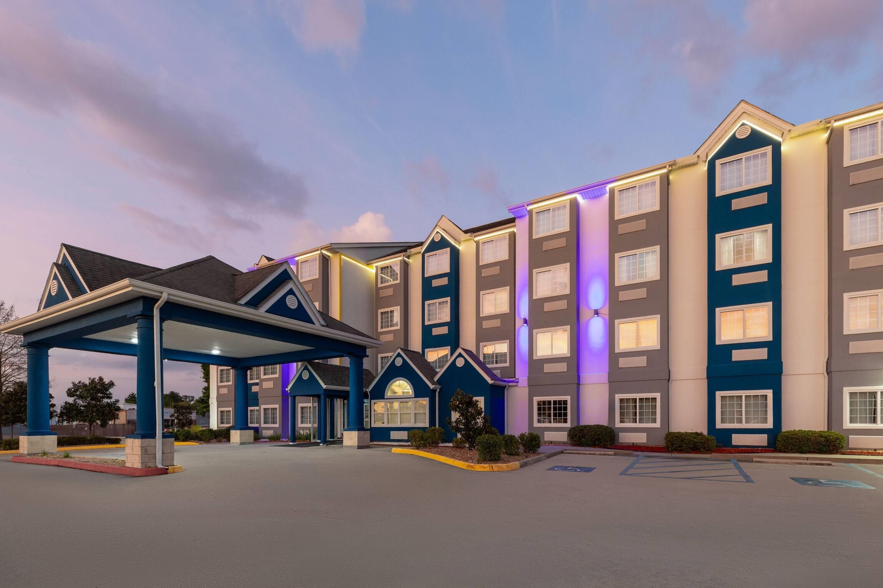 A multi-story hotel with a covered entrance, a parking lot, and a well-maintained landscape.