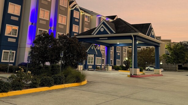 A hotel with a blue facade, multiple windows, and a covered entrance. - Microtel Inn & Suites by Wyndham Baton Rouge Airport (Baton Rouge)