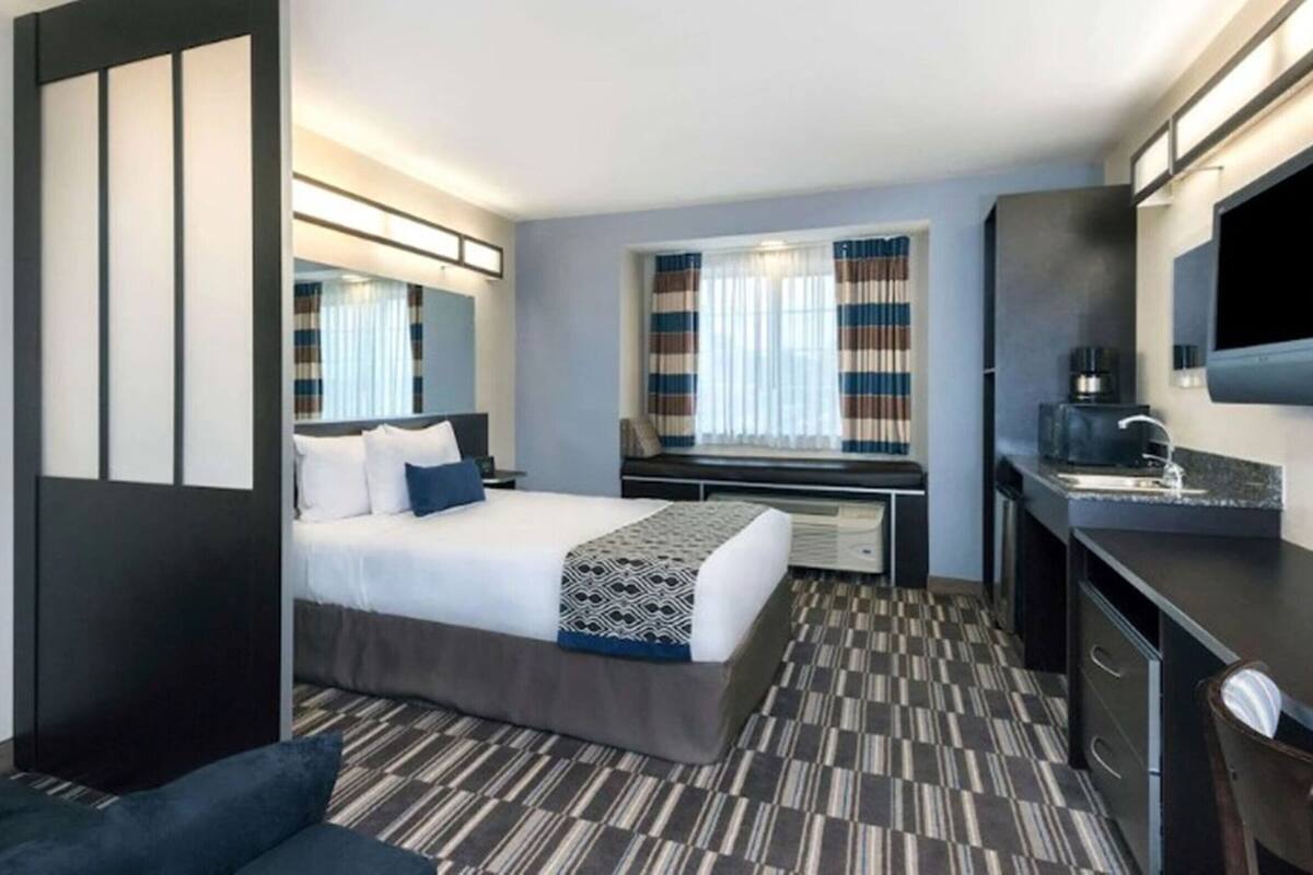 A hotel room with a bed, a desk, a TV, and a seating area.