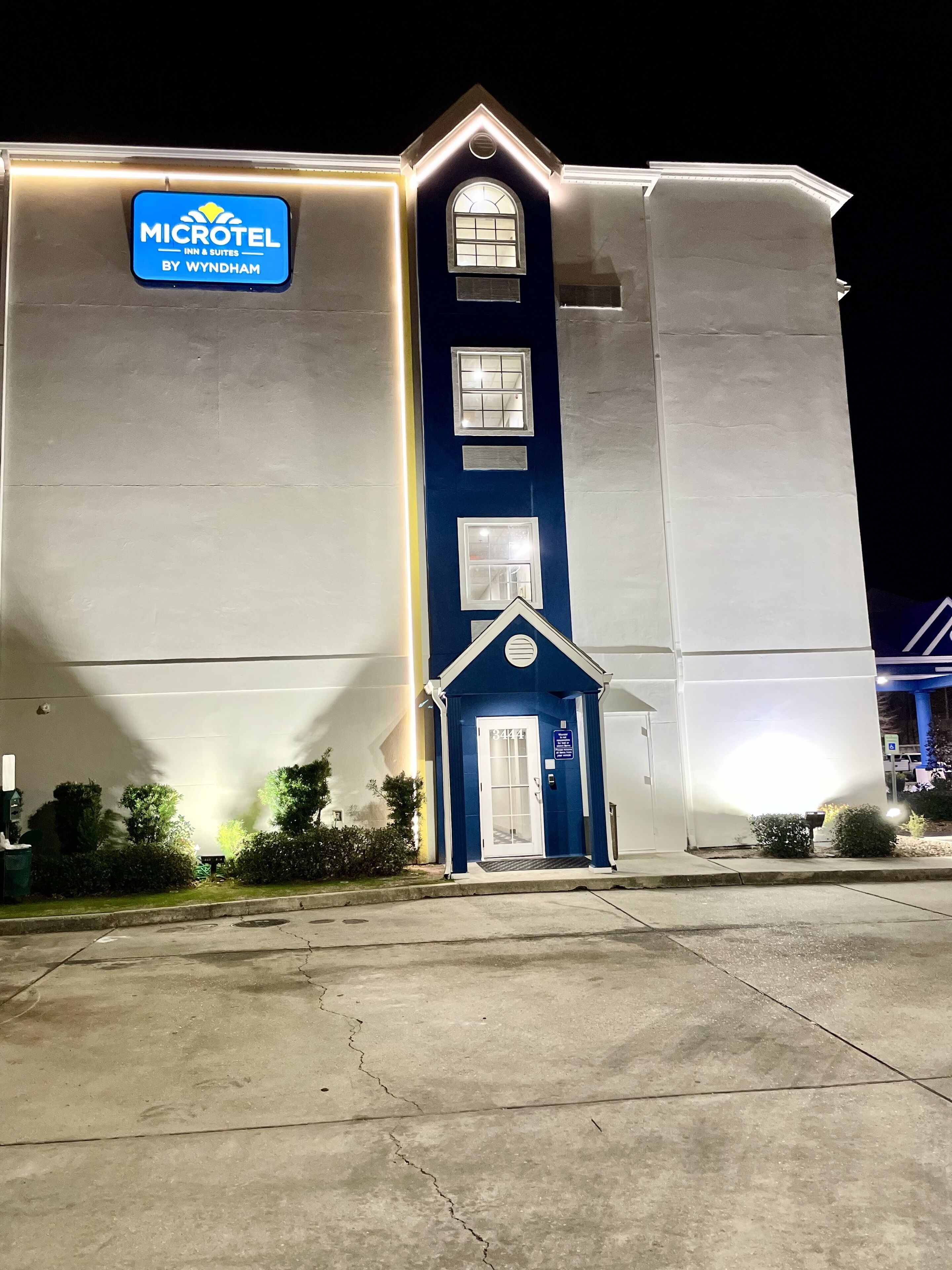 A Microtel Inn & Suites by Wyndham with a prominent sign, a small entrance with a door marked 3444, and a large building facade.