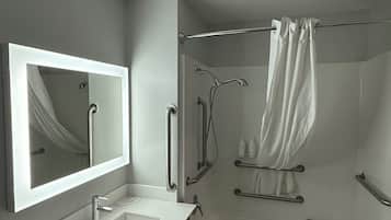 A modern bathroom with a large mirror, a sink, and a bathtub.