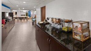 A modern kitchen with a long counter, a coffee station, and a seating area in the background. - Microtel Inn & Suites by Wyndham Baton Rouge Airport (Baton Rouge)