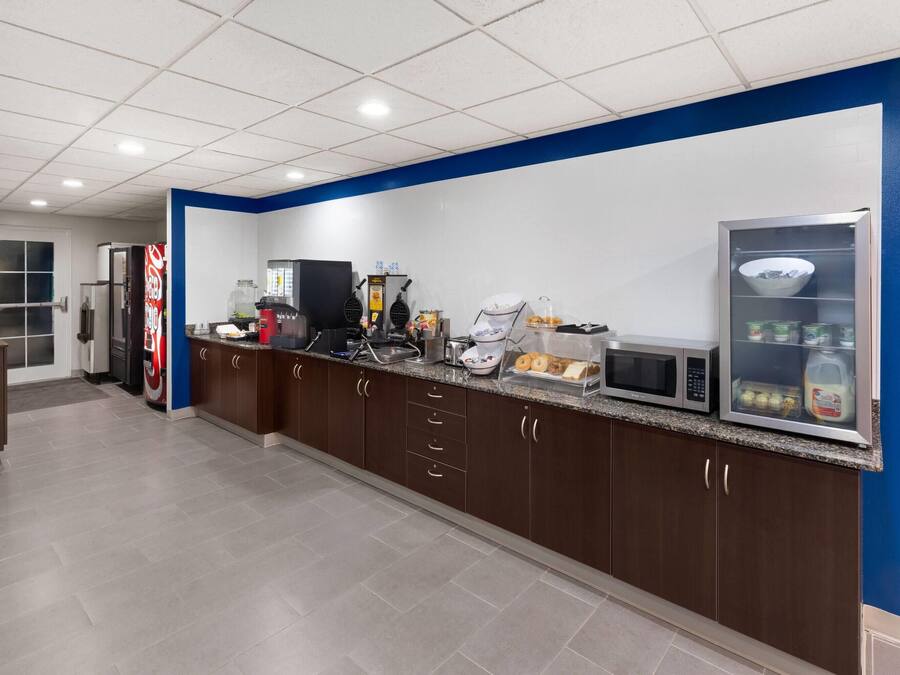 A kitchen with a microwave, toaster, and refrigerator, and a blue accent wall.