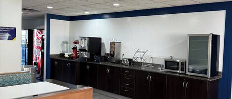 A modern kitchen with dark cabinets, a wooden countertop, and a microwave.