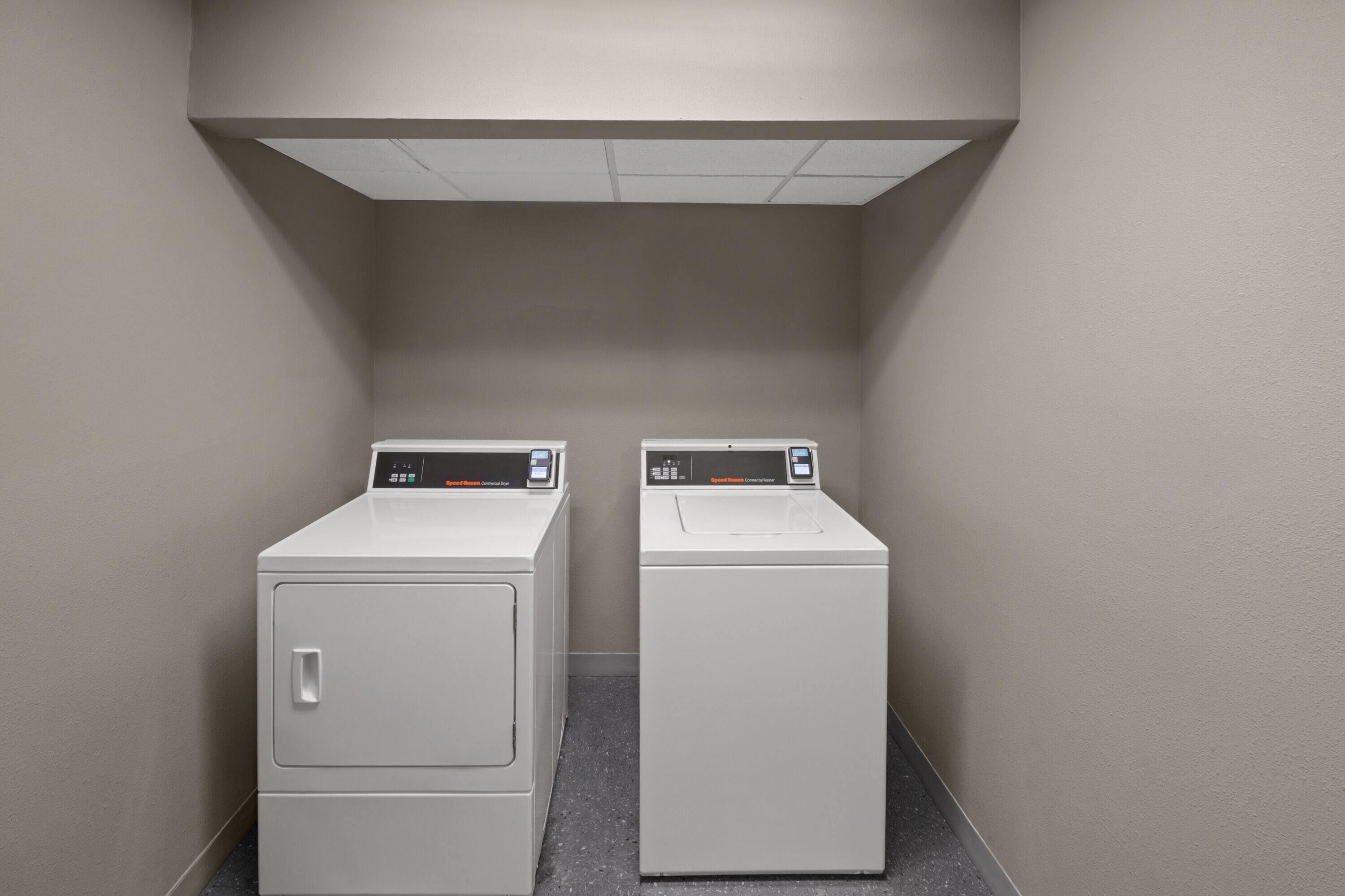Une buanderie équipée de deux machines à laver à chargement frontal et d’un panneau de commande situé au-dessus.