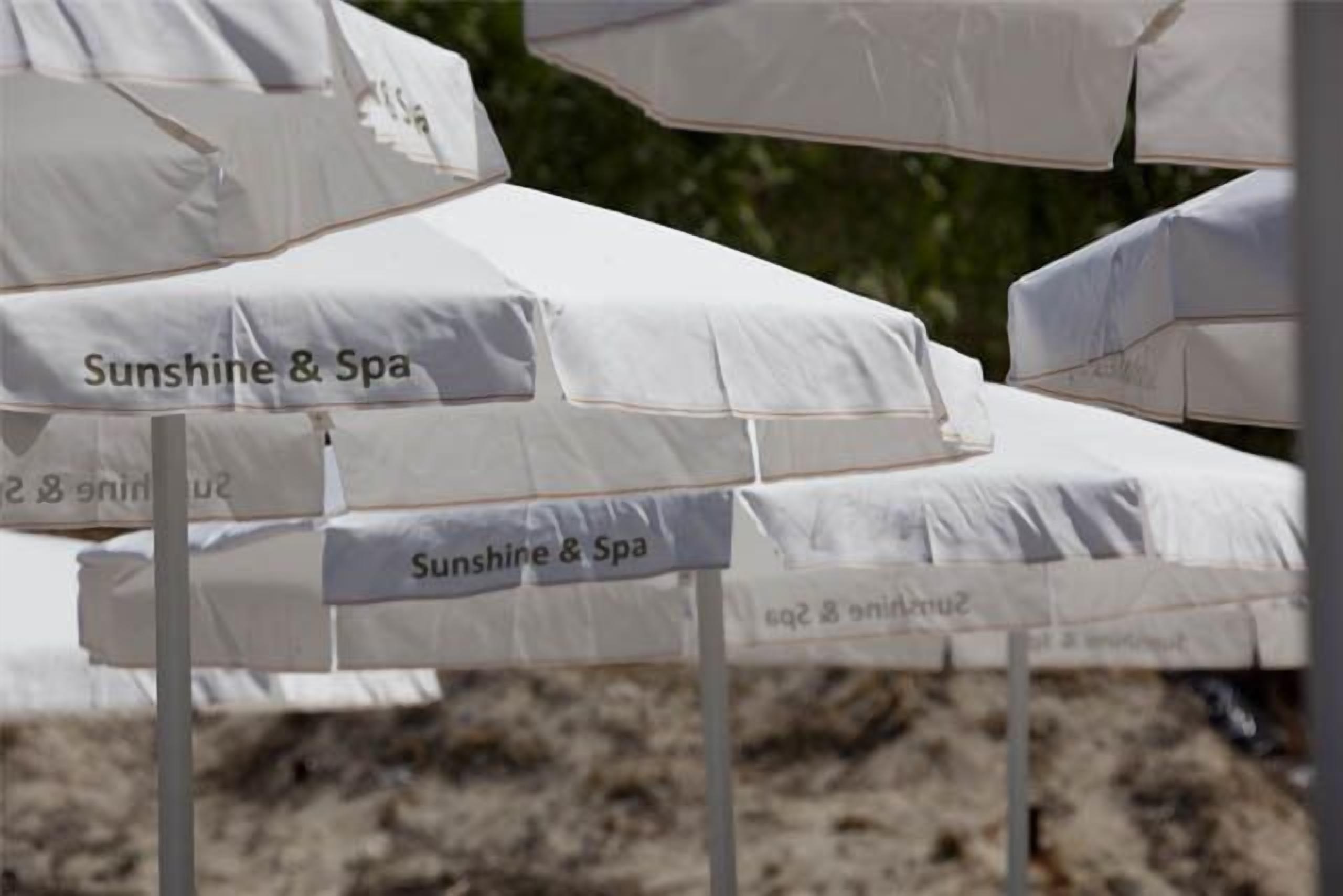 Varias sombrillas blancas con el rótulo 'Sunshine & Spa', señalando un área de spa.