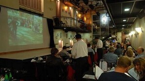 Un bar bondé où un grand écran diffuse une présentation.