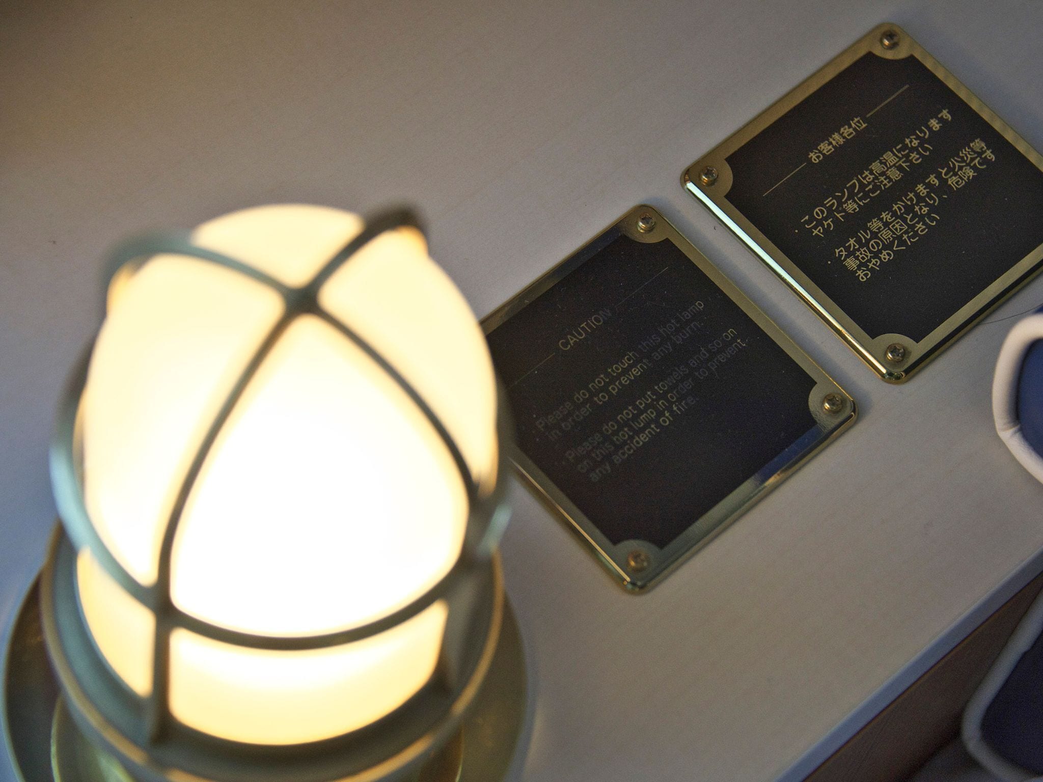 A table with a lit lamp and two plaques with cautionary text.