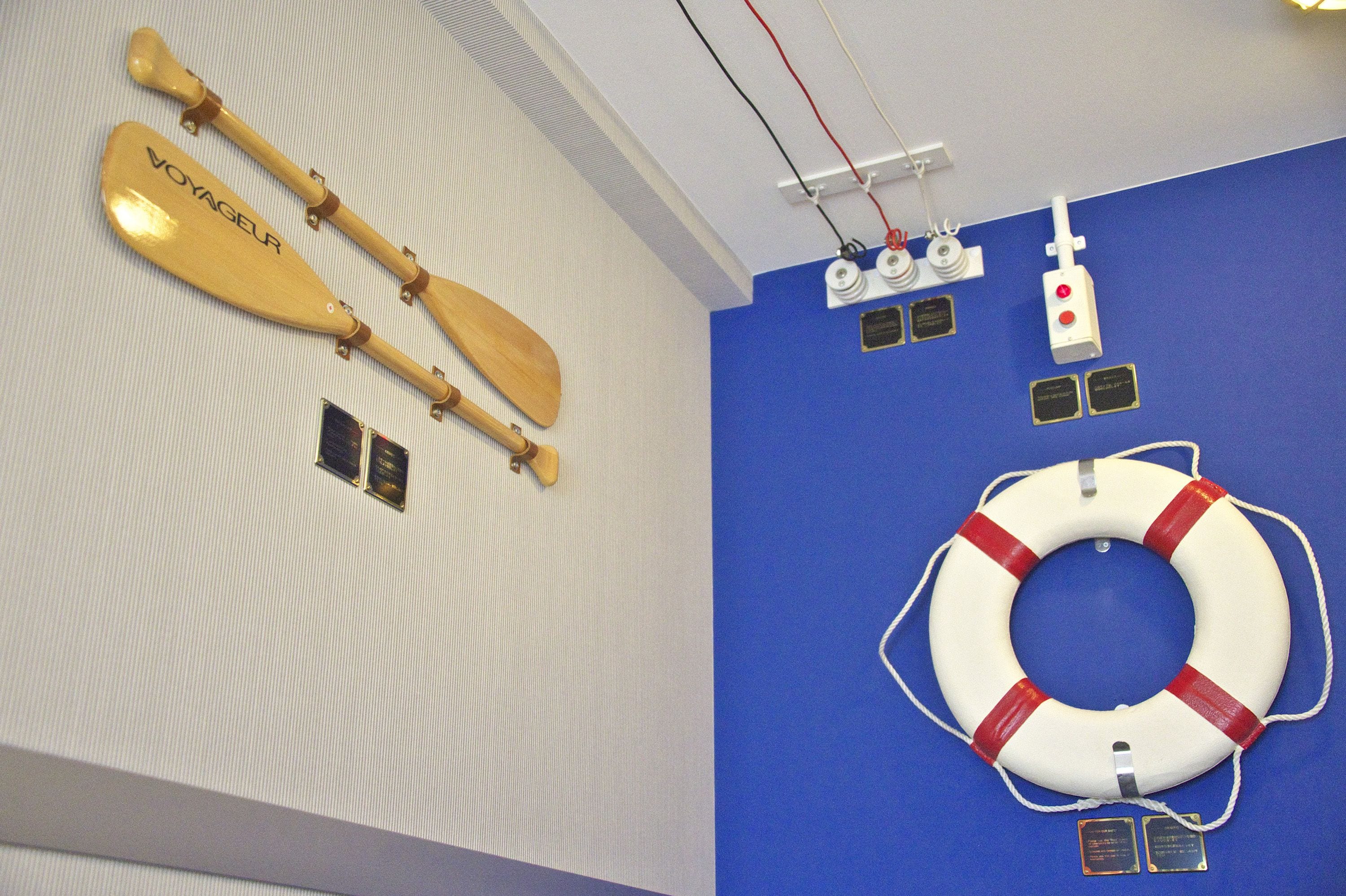 A wall with two wooden paddles labeled "VOYAGEUR" and a life preserver with plaques.