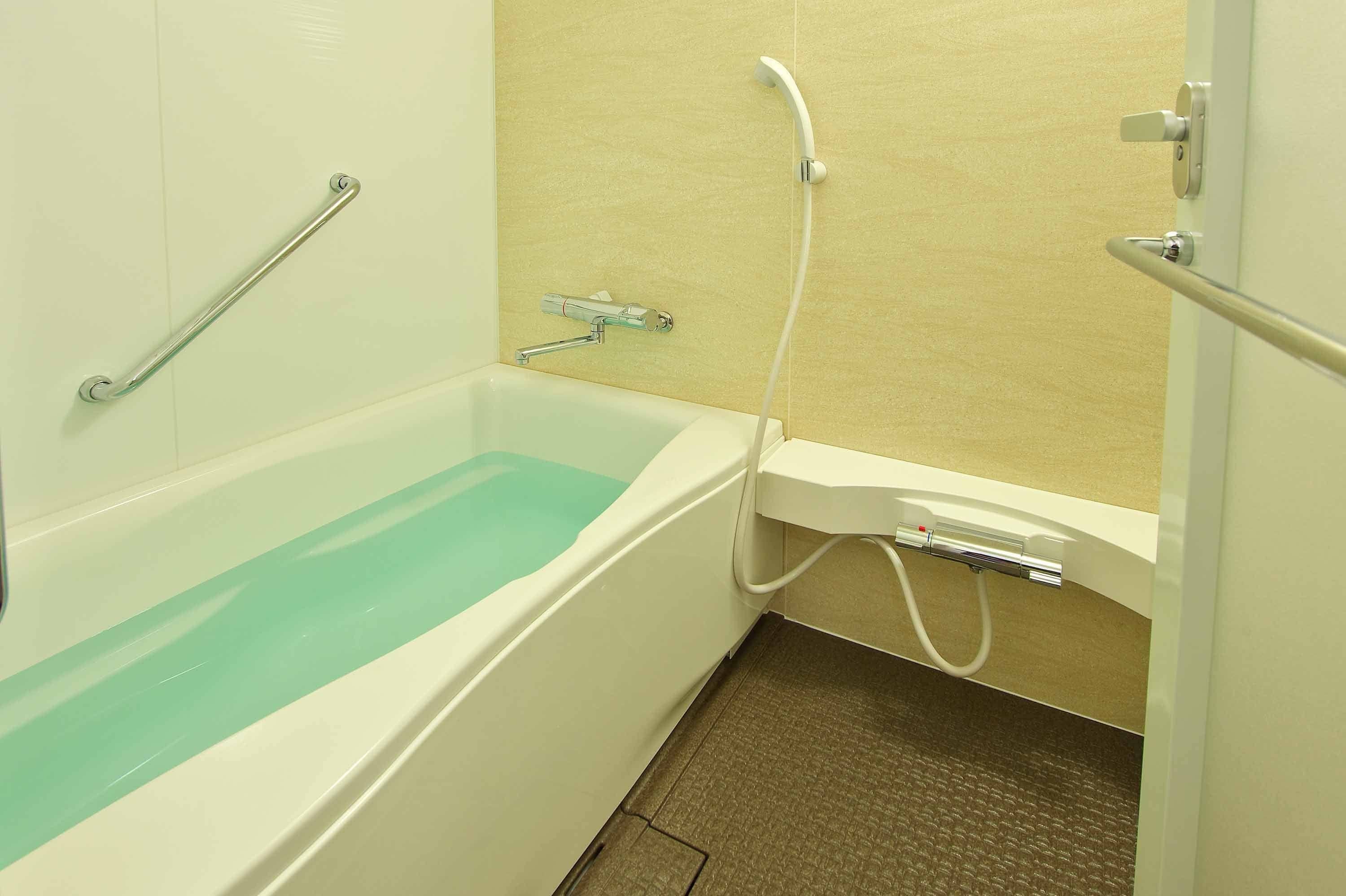 A bathroom with a bathtub, a shower, and a handrail.