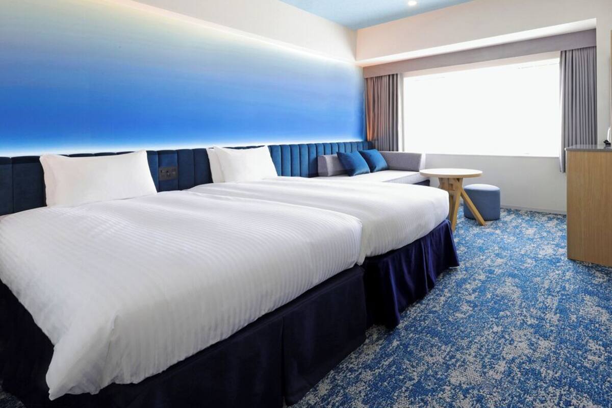 A hotel room with a large bed, a seating area, a small table, and a view of the outdoors.
