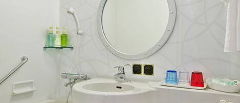 A bathroom with a white sink, mirror, and toilet. There are toiletries on the counter and a showerhead above the sink.
