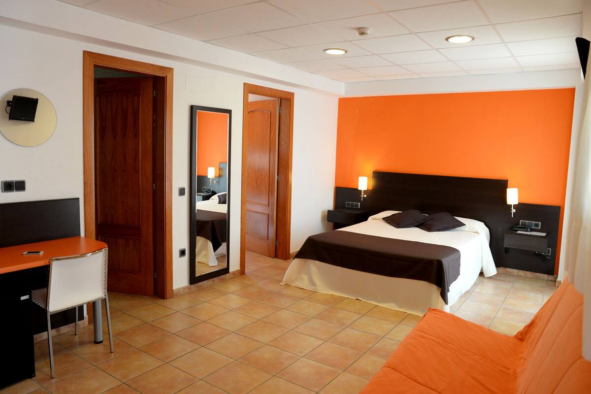 A hotel room with a bed, a desk, and a chair.