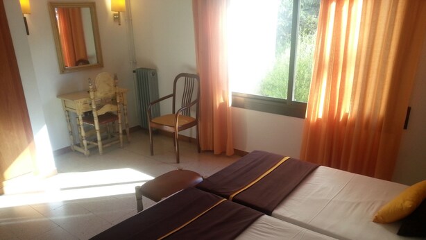 Een hotelkamer met twee bedden, een bureau en een stoel.