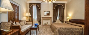 A hotel room with a sofa, a bed, a small table, a fireplace, and two lamps. - Hotel Dell'Opera (Venice)