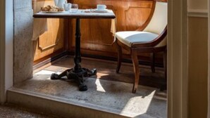 Une pièce d’angle avec une table et une chaise, une fenêtre et une vue sur un bâtiment à l’extérieur.