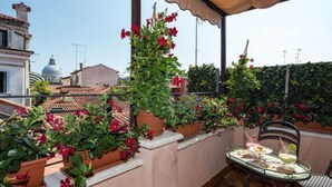 Une terrasse sur le toit, agrémentée de plantes en pot et d’une table dressée pour le repas.