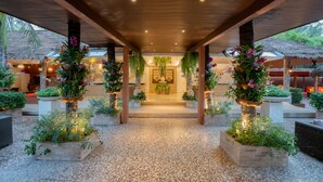 An outdoor covered area with a tiled floor, wooden pillars, and potted plants. - Dhevan Dara Resort & Spa (Hua Hin)