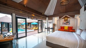 A spacious bedroom with a large bed, a glass door leading to a pool area, and a dining table with chairs. - Dhevan Dara Resort & Spa (Hua Hin)