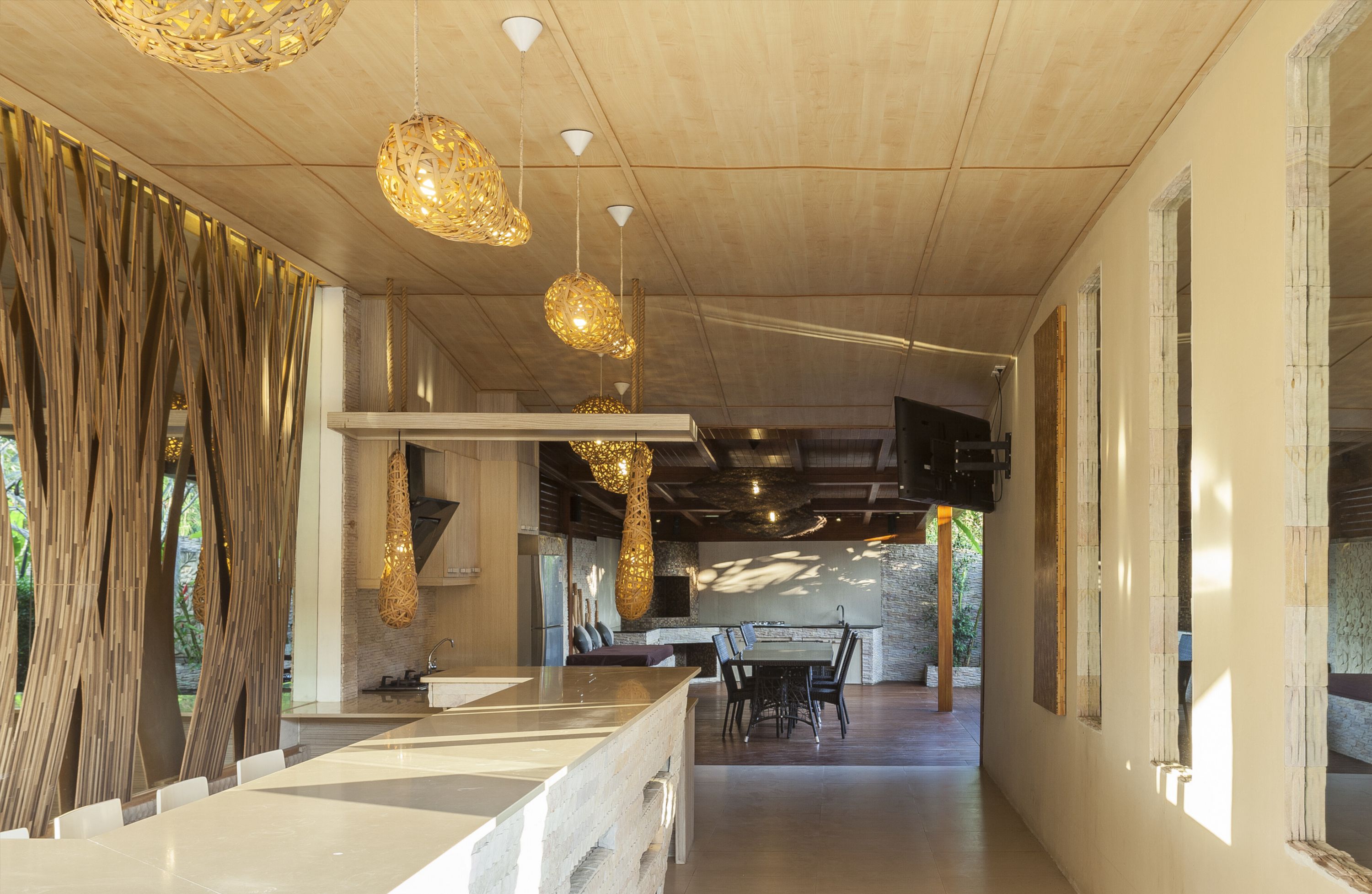 A modern kitchen with a central island, pendant lighting, and a view to the outdoor area.